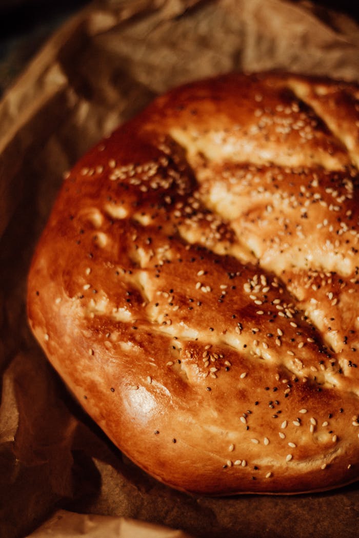 services-03 Close-up of rustic homemade bread with sesame seeds, freshly baked on craft paper.